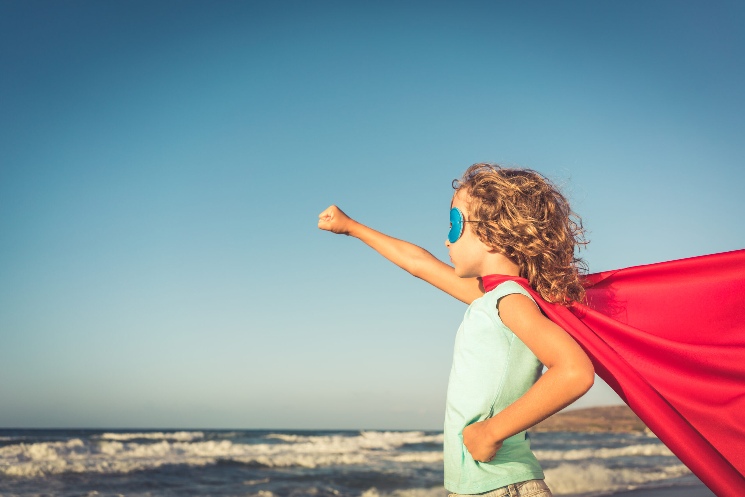 Superhero child on the beach. Summer vacation concept